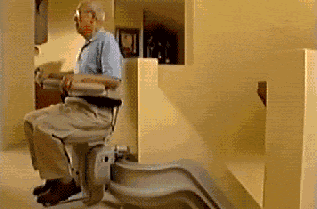 old man seated on a chair going down the stairs towards flames