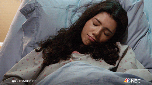 Une jeune femme sourit dans son lit.