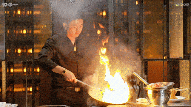 Un homme cuisine avec des flammes.